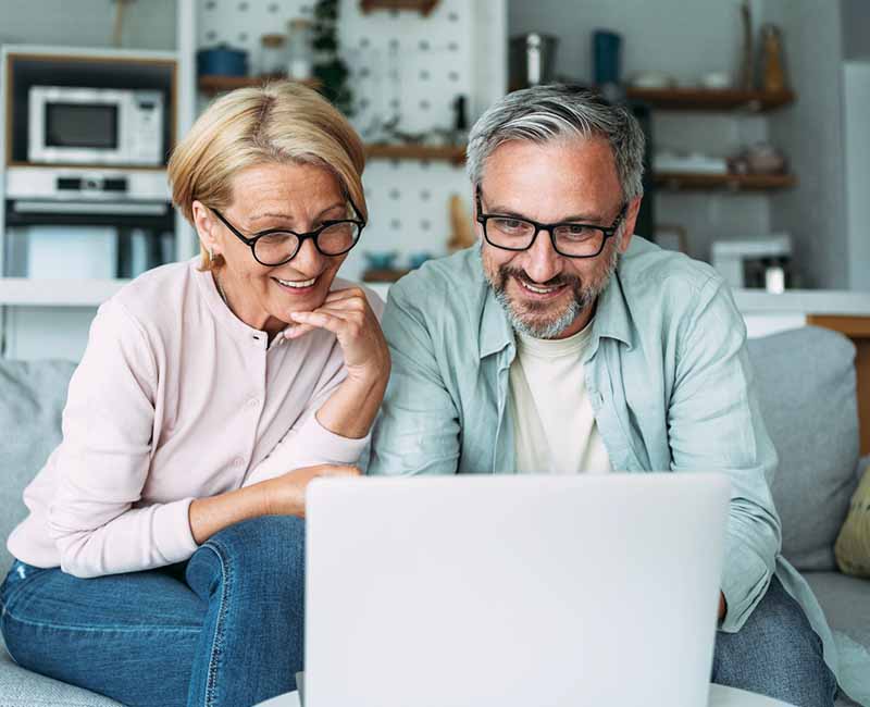 mature couple smiling while looking at laptop together